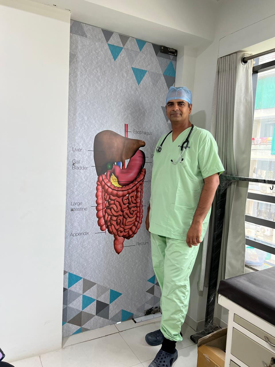 Dr. Urvish Doshi beside the gastrointestinal anatomy chart